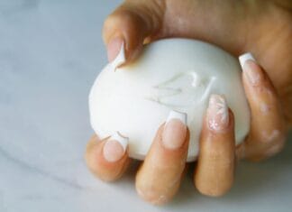 Delikatny french manicure krok po kroku: poradnik dla początkujących i gotowe inspiracje Dłoń z delikatnym french manicure trzymająca biały ozdobny kostkę mydła