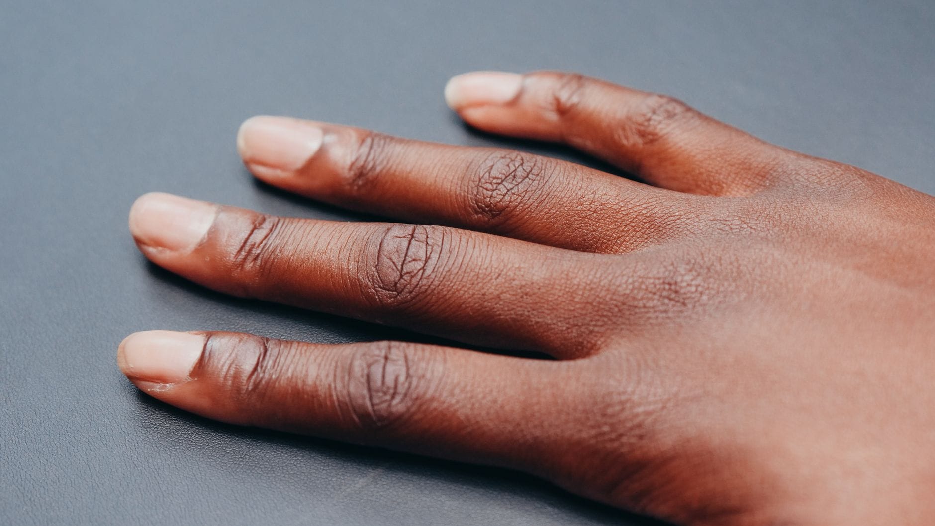 Zbliżenie dłoni z delikatnym french manicure na neutralnym tle