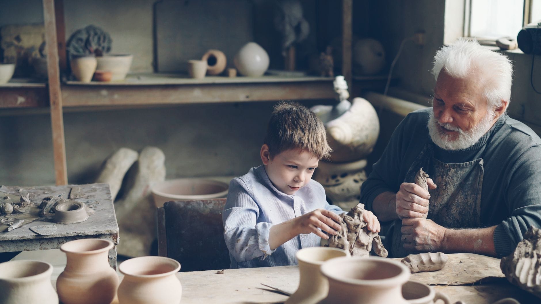 Dziadek z wnuczkiem lepią razem ceramikę w przytulnej pracowni