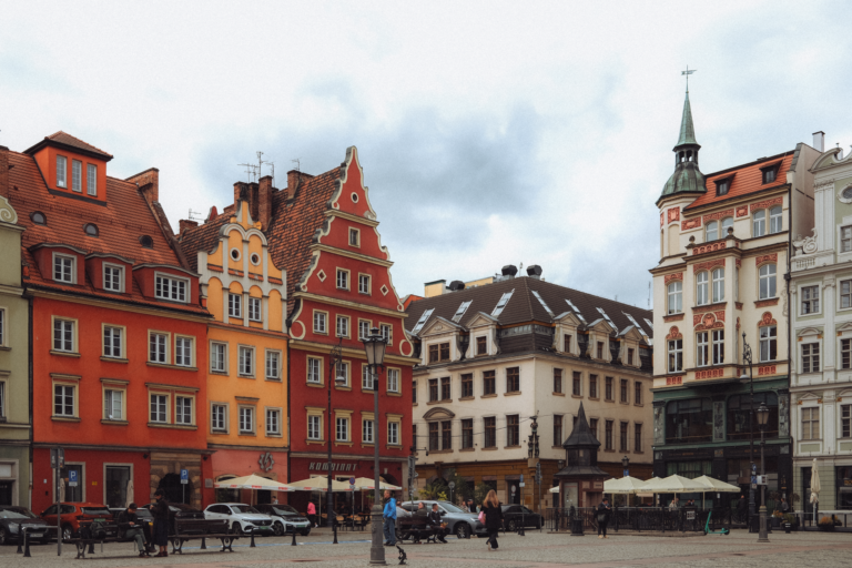 Kolorowe kamienice z podcieniami na wrocławskim rynku pod chmurami